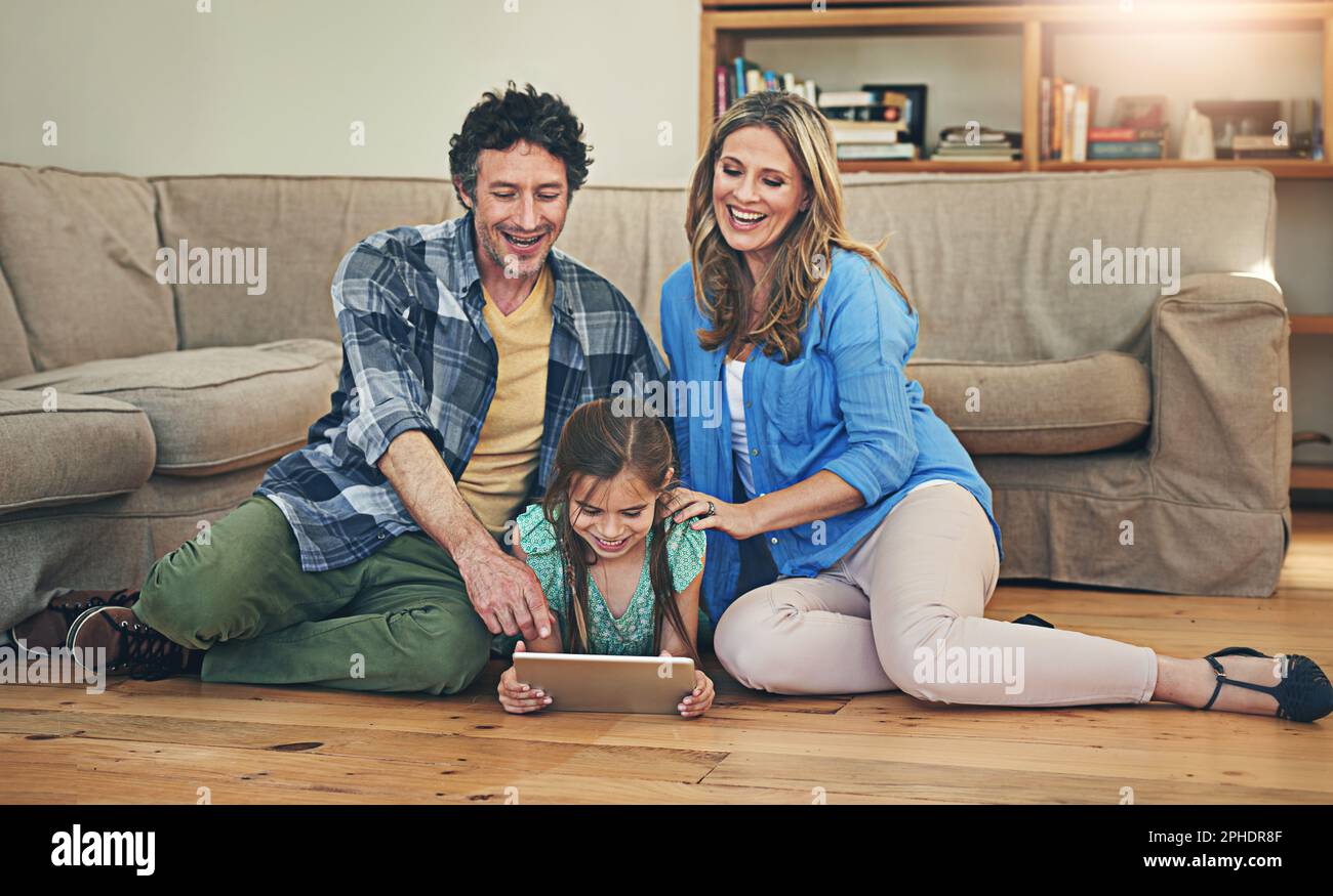 Mit den richtigen Apps macht die Familie Spaß. Eine glückliche Familie, die zu Hause ein digitales Tablet zusammen verwendet. Stockfoto