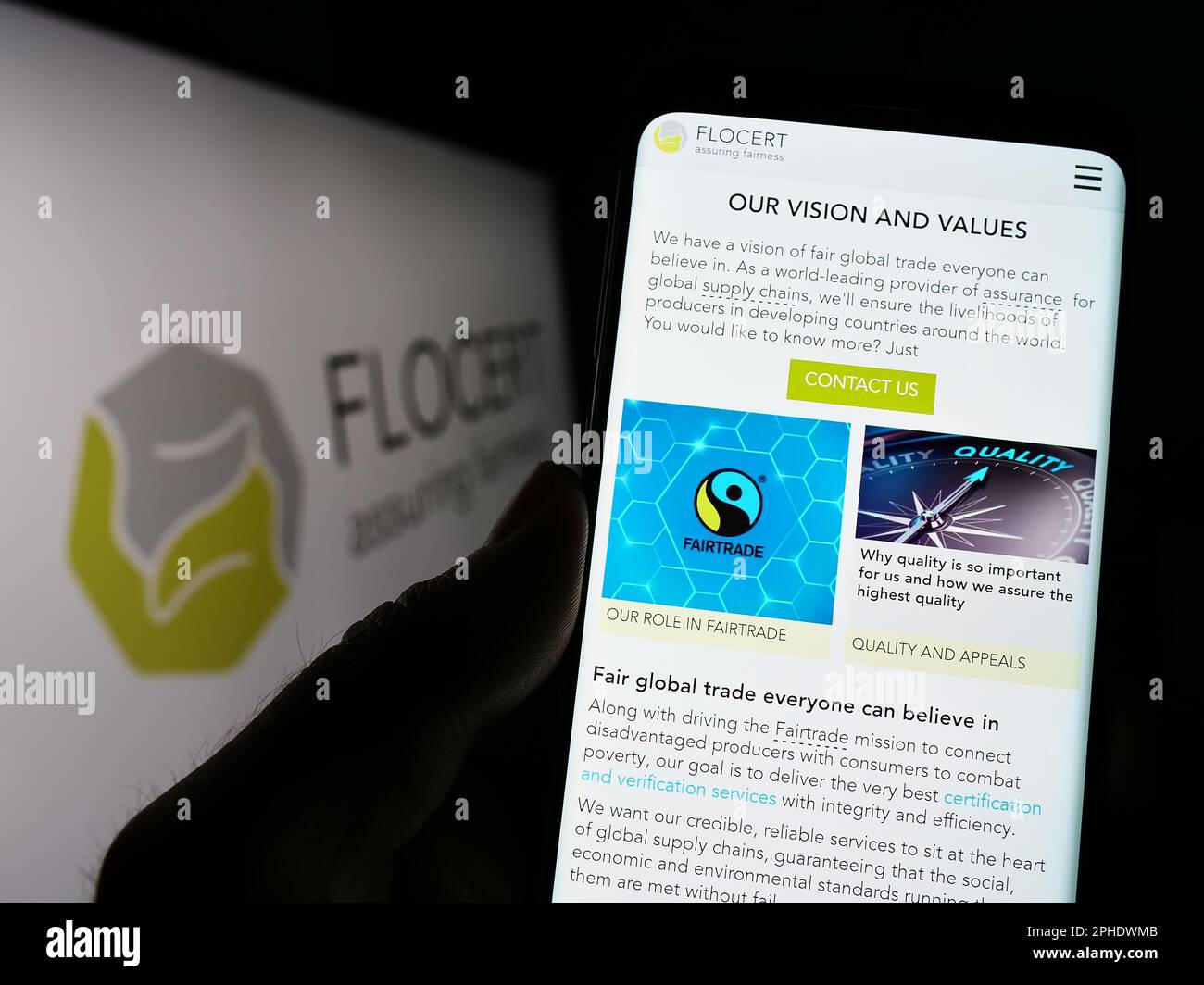 Person mit Smartphone und Webseite der Produktzertifizierungseinrichtung FLOCERT GmbH auf dem Bildschirm mit Logo. Konzentrieren Sie sich auf die Mitte des Telefondisplays. Stockfoto