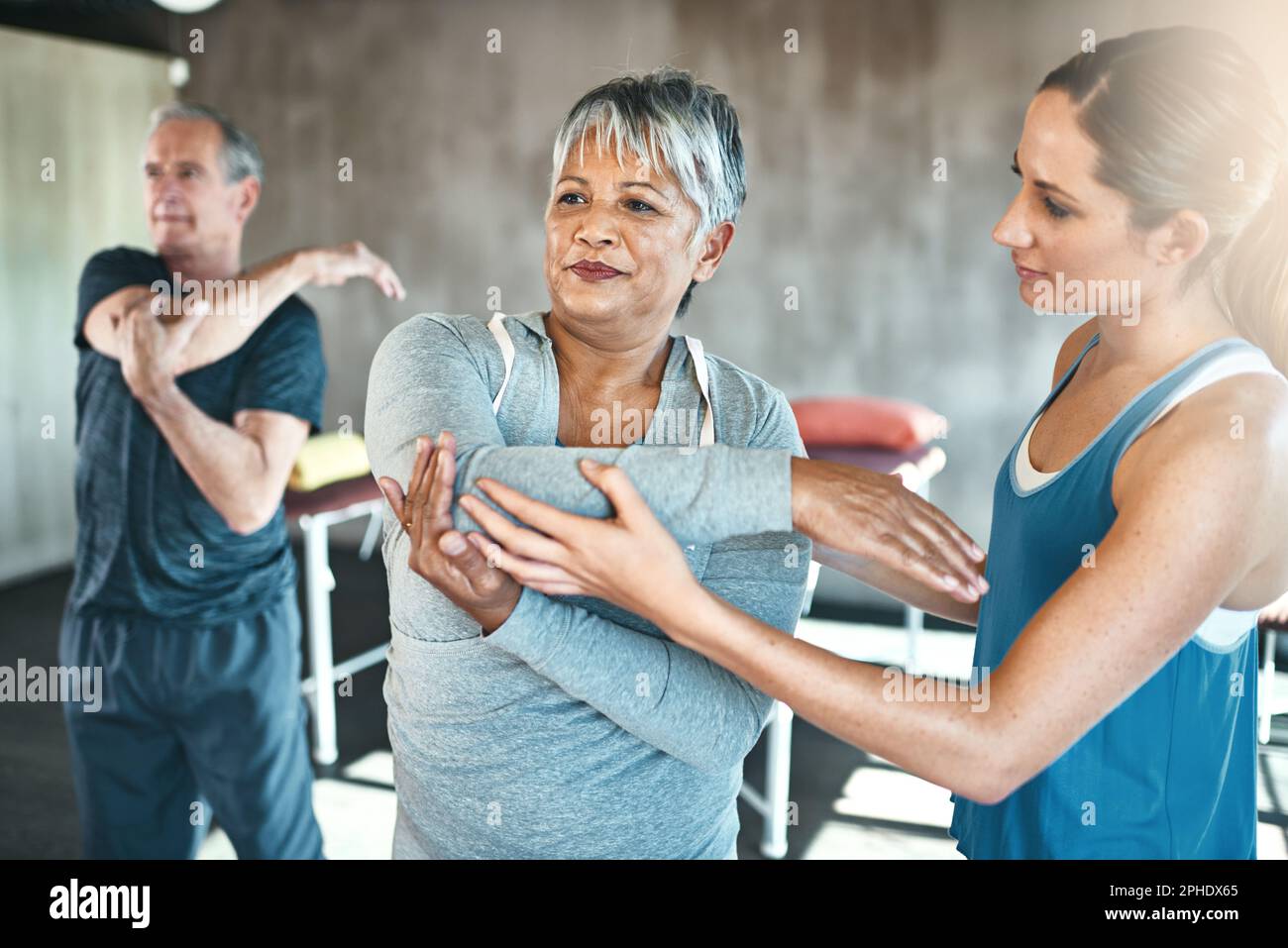 Körperliche Aktivität hilft, die allgemeine Muskelgesundheit zu verbessern. Ein älterer Mann und eine ältere Frau, die mit Hilfe eines Lehrers trainieren. Stockfoto