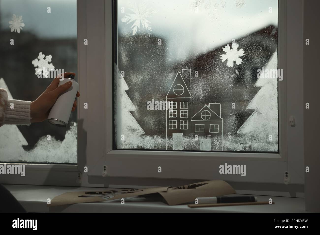 Eine Frau, die Schneespray benutzt, um zu Hause Fenster zu dekorieren,  Nahaufnahme Stockfotografie - Alamy