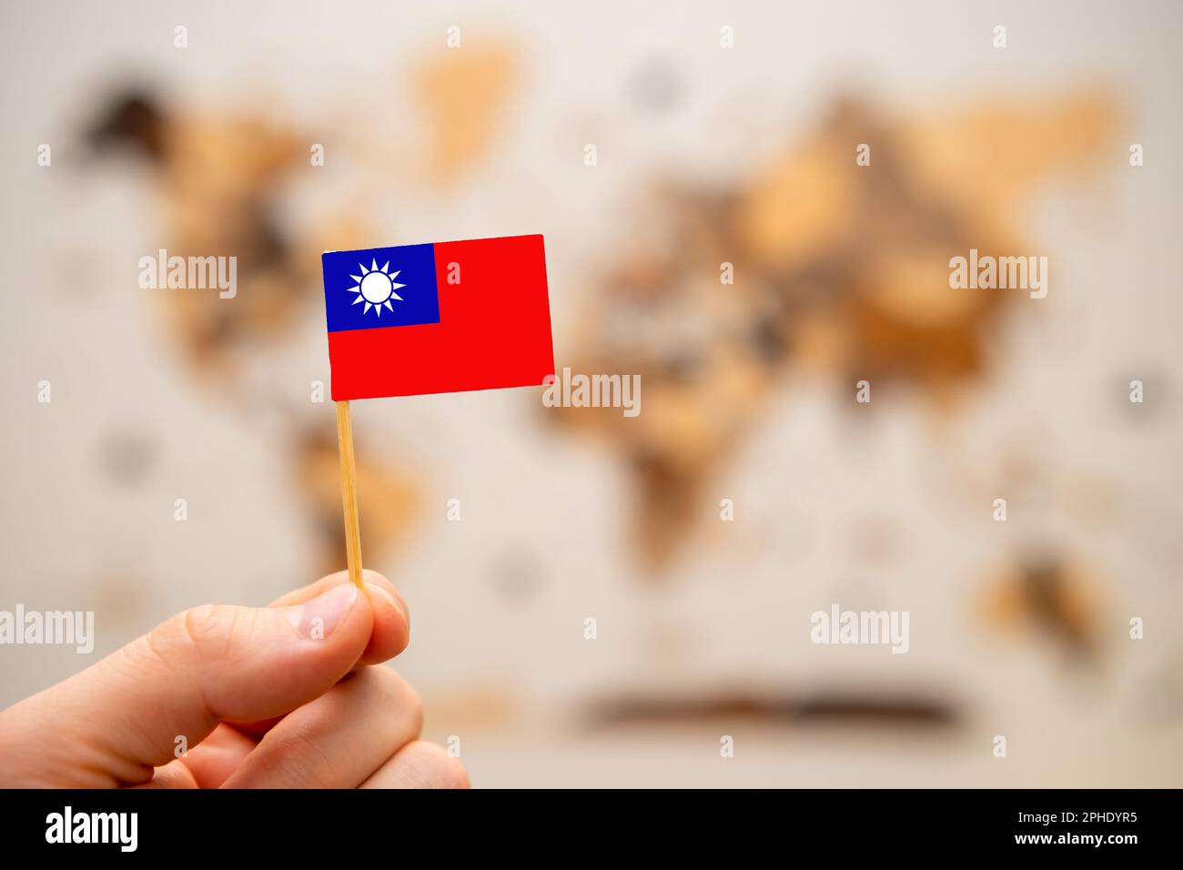 Taiwan-Flagge in der hand auf dem hölzernen Hintergrund der Weltkarte. Weltwirtschaft und geopolitisches Konzept. Stockfoto