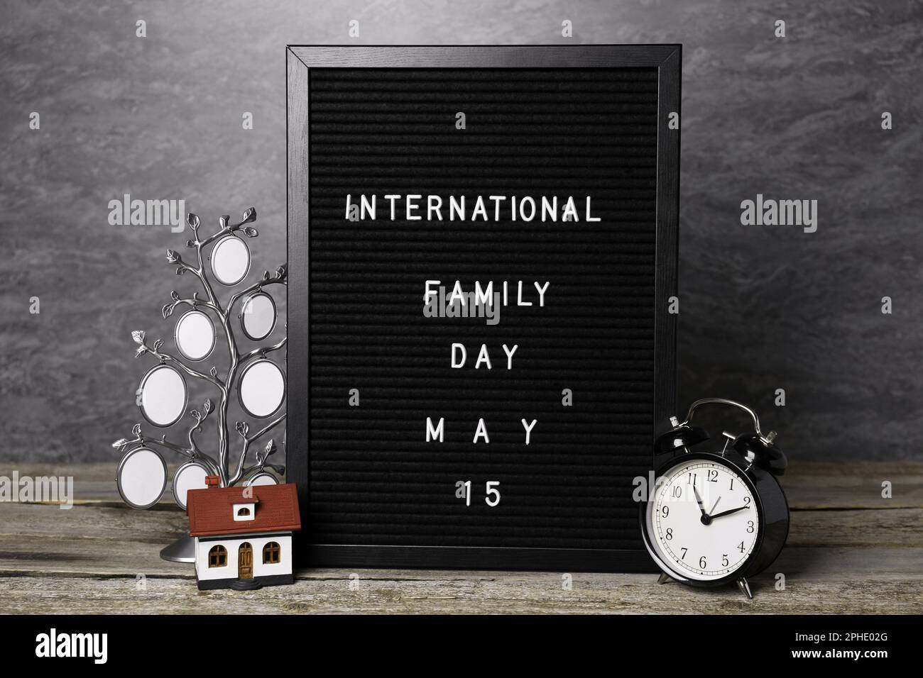 Alles Gute Zum Familientag. Schwarzes Brieftafel mit Text, Uhr, Hausmodell und Bilderrahmen auf Holztisch Stockfoto