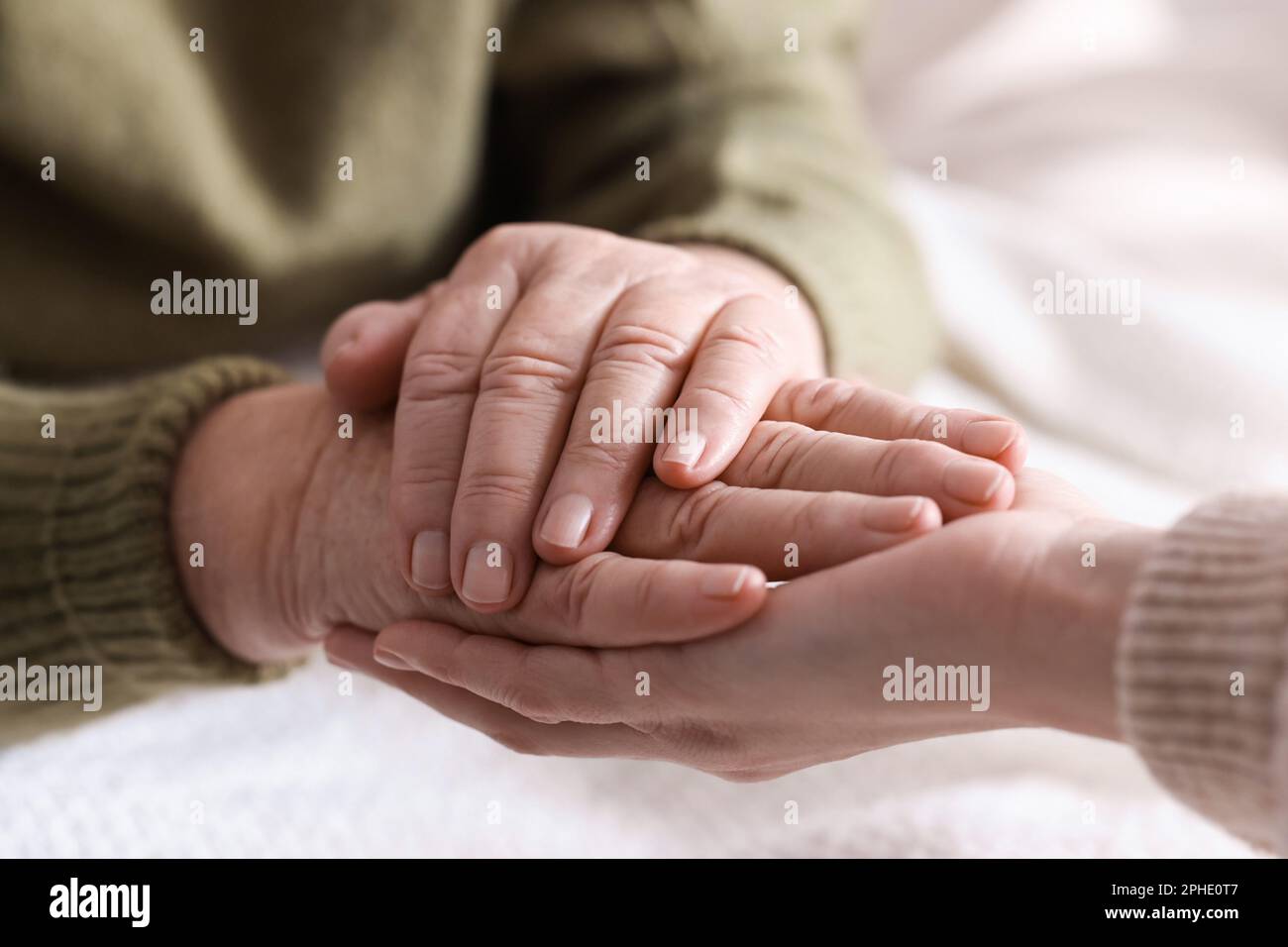 Junge und ältere Frauen, die sich in geschlossenen Räumen an den Händen halten, Nahaufnahme Stockfoto