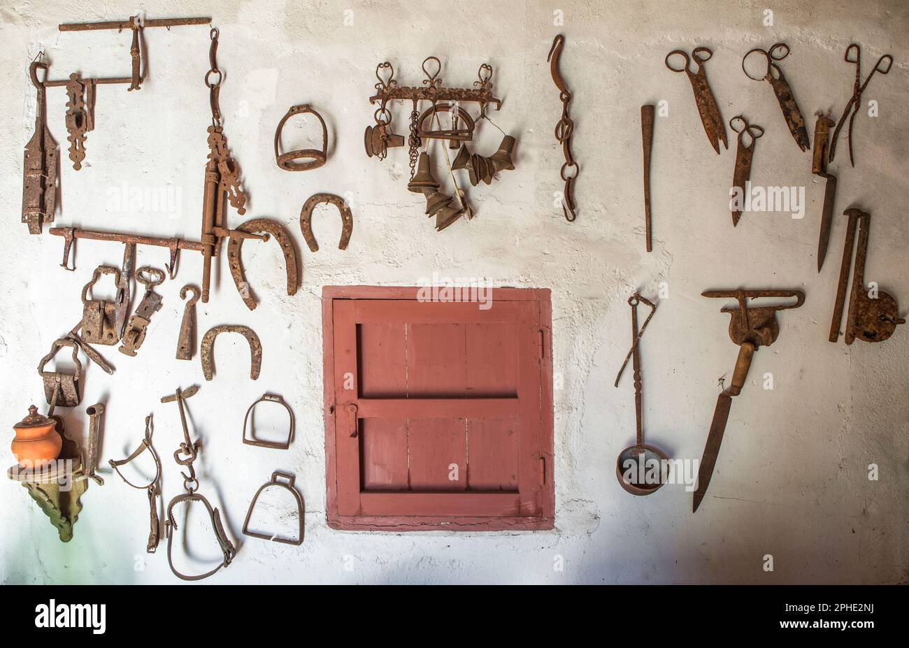 Alte landwirtschaftliche Geräte, die an der Wand hängen. Hintergrund im Landhausstil Stockfoto