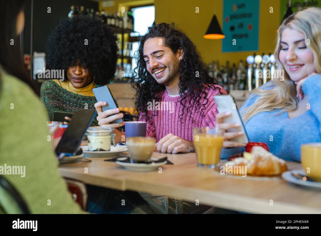 Der Content Creators Breakfast, ein junger langhaariger Kerl, nutzt sein Smartphone, um Inhalte online zu teilen, Leute, die Essen fotografieren und soziale n nutzen Stockfoto