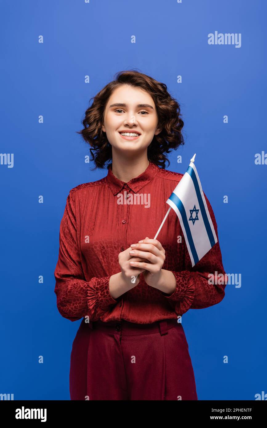 Fröhlicher Lehrer der hebräischen Sprache hält die Flagge Israels isoliert auf blauem Stockbild Stockfoto
