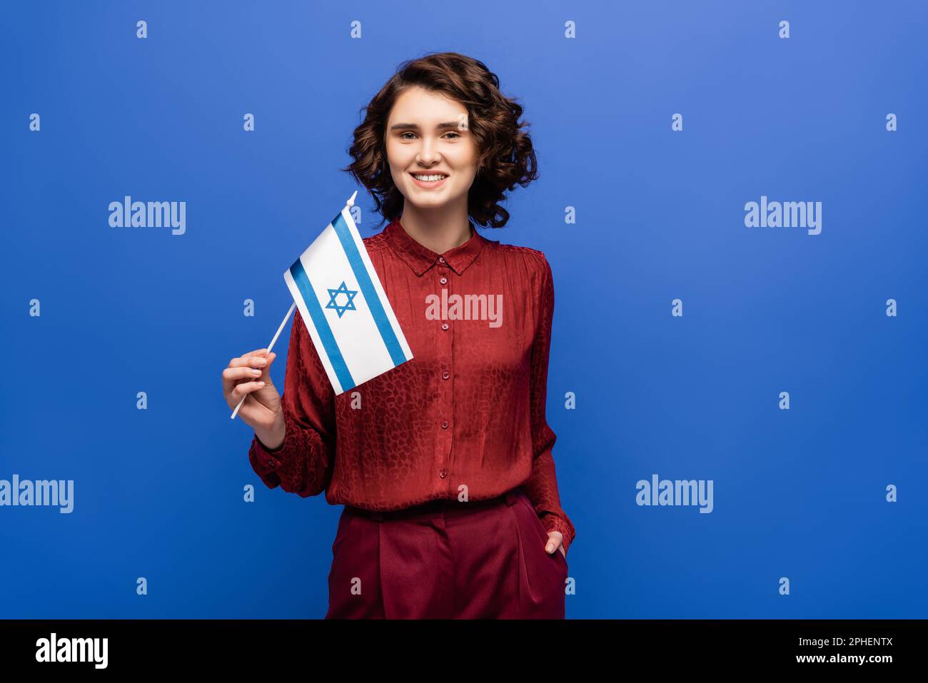Glücklicher Lehrer der hebräischen Sprache hält die Flagge Israels isoliert auf blauem Stockbild Stockfoto