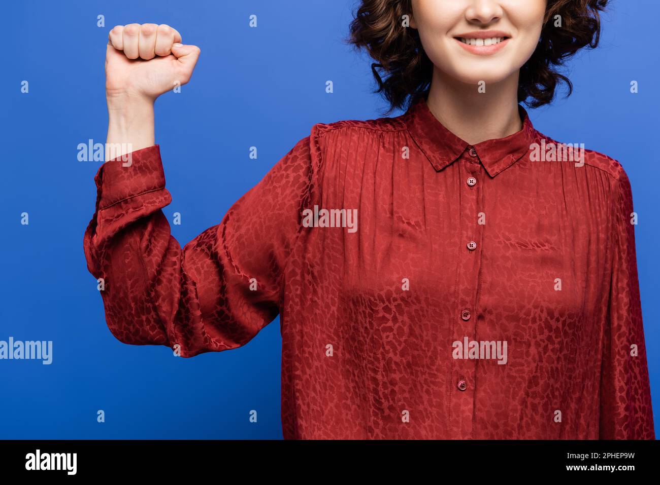 Zugeschnittene Ansicht eines Lächelpädagogen für Gebärdensprache mit isolierter Geste auf blauem Stockbild Stockfoto