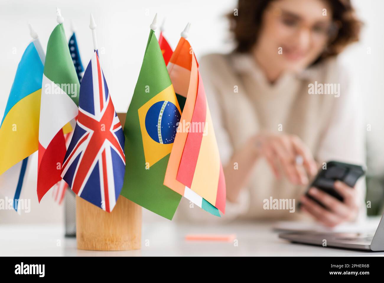 Internationale Flaggen verschiedener Länder in der Nähe von Sprachlehrern auf verschwommenem Hintergrund, Stockbild Stockfoto