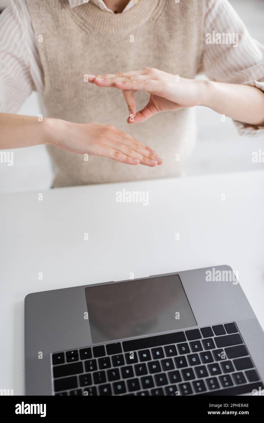 Zugeschnittene Ansicht des Lehrers, die während des Online-Unterrichts eine Geste in der Zeichensprache auf dem Laptop zeigt, Stockbild Stockfoto