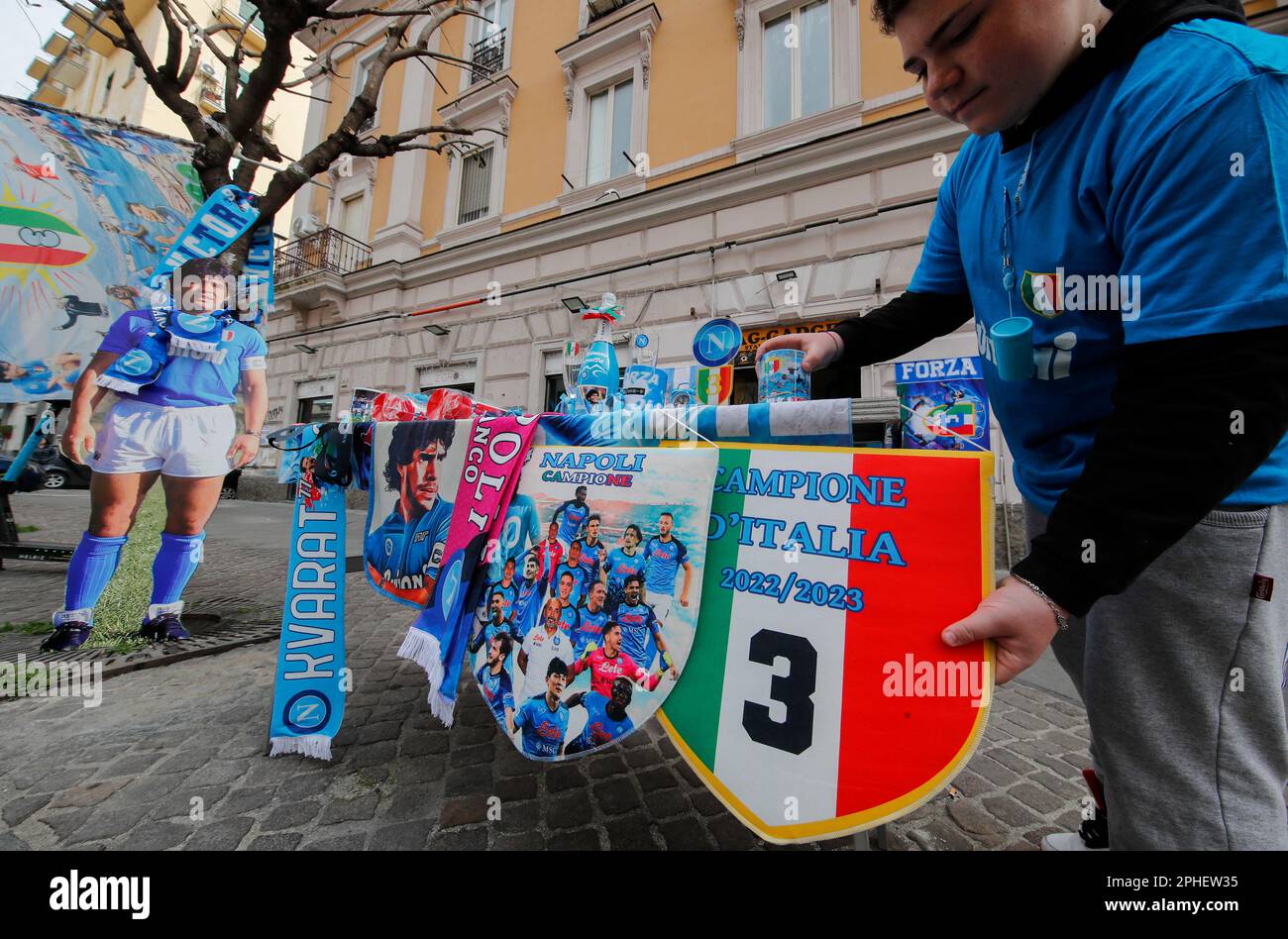 Neapel, Italien. 11. März 2023. Ein Junge stellt einen Stand mit Champagnerflaschen auf, in dem das Bild von Diego Armando Maradona, Flaggen und andere Gegenstände vor einem Geschäft ausgestellt sind. In der Stadt beginnen die Vorbereitungen, um den Sieg der Fußballliga der Serie A von SSC Napoli zu feiern, die derzeit den ersten Platz in der Rangliste belegt, mit 18 Punkten vor dem zweiten, wobei noch 12 Spiele zu spielen sind. Nach den Siegern in den Jahren 1987 und 1990 wäre dies die dritte Trophäe von Neapel in der italienischen Spitzenliga Scudetto, mit Diego Armando Maradona auf dem Spielfeld. Kredit: Unabhängige Fotoagentur/Alamy Live News Stockfoto