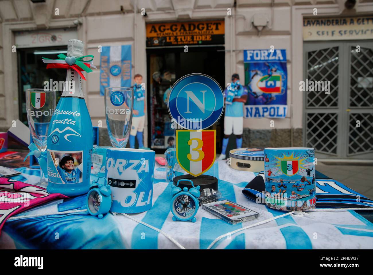 Neapel, Italien. 11. März 2023. Eine Champagnerflasche mit dem Bild von Diego Armando Maradona, Flaggen und andere Geräte werden vor einem Geschäft ausgestellt. In der Stadt beginnen die Vorbereitungen, um den Sieg der Fußballliga der Serie A von SSC Napoli zu feiern, die derzeit den ersten Platz in der Rangliste belegt, mit 18 Punkten vor dem zweiten, wobei noch 12 Spiele zu spielen sind. Nach den Siegern in den Jahren 1987 und 1990 wäre dies die dritte Trophäe von Neapel in der italienischen Spitzenliga Scudetto, mit Diego Armando Maradona auf dem Spielfeld. Kredit: Unabhängige Fotoagentur/Alamy Live News Stockfoto
