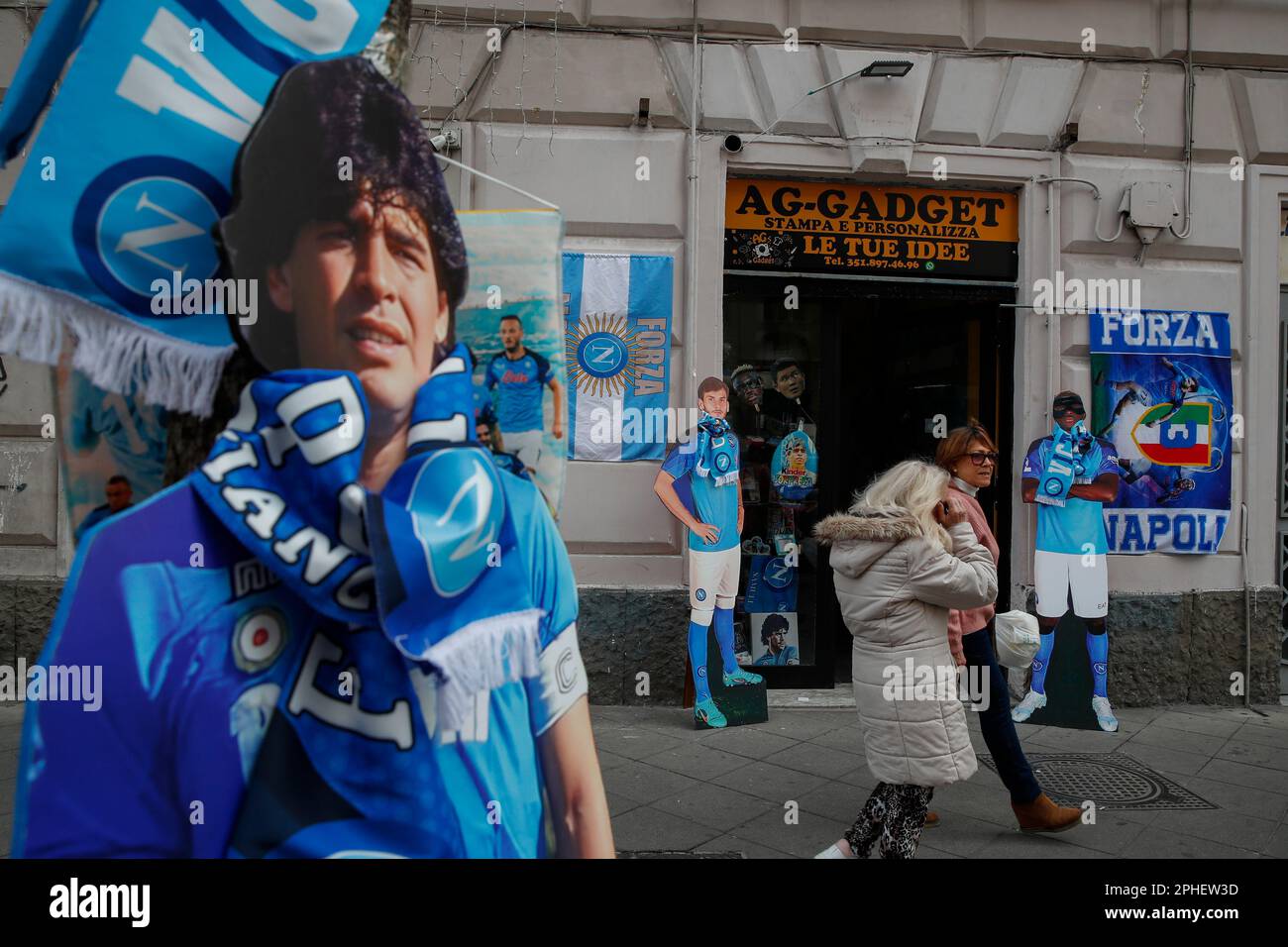 Eine lebensgroße Silohuette von Diego Armando Maradona, zwei weiteren SSC Napoli Fußballverein-Spielern Kvicha Kvaraskelia und Victor Osimhen, Flaggen und andere Gegenstände werden vor einem Geschäft ausgestellt. In der Stadt beginnen die Vorbereitungen, um den Sieg der Fußballliga der Serie A von SSC Napoli zu feiern, die derzeit den ersten Platz in der Rangliste belegt, mit 18 Punkten vor dem zweiten, wobei noch 12 Spiele zu spielen sind. Nach den Siegern in den Jahren 1987 und 1990 wäre dies die dritte Trophäe von Neapel in der italienischen Spitzenliga Scudetto, mit Diego Armando Maradona auf dem Spielfeld. Stockfoto