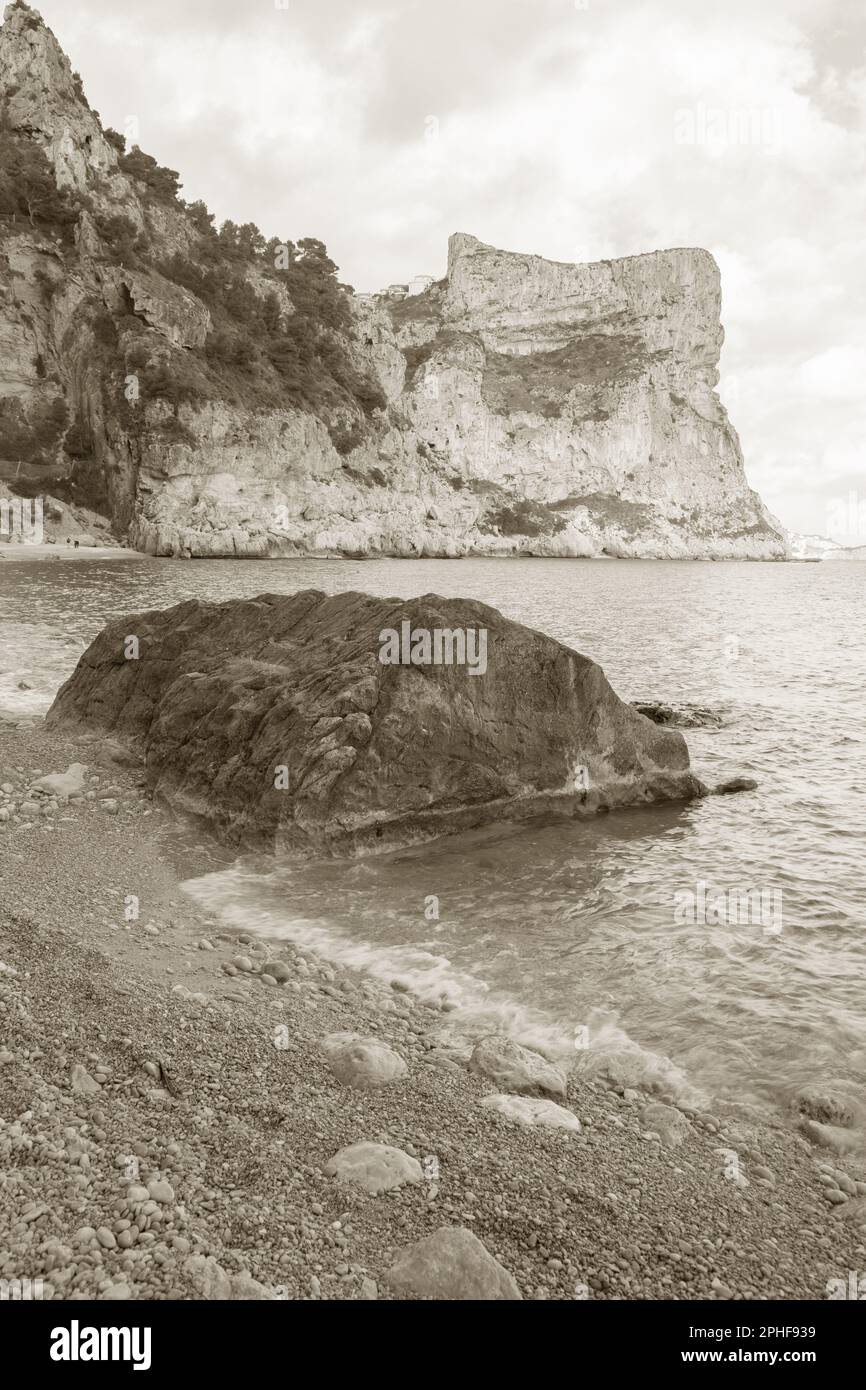 Landschaftsblick am Moraig Cove Beach mit Felsen, Alicante, Spanien in Schwarzweiß-Sepia-Farbtönen Stockfoto