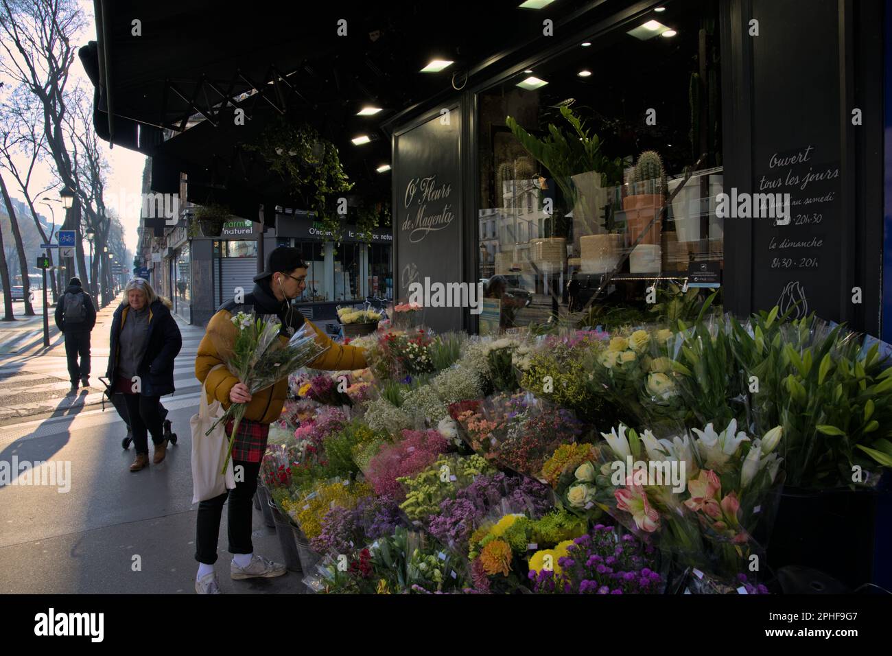 Ein junger Mann in modischer Kleidung, der am Morgen des Valentinstages in Paris Blumen kauft Stockfoto