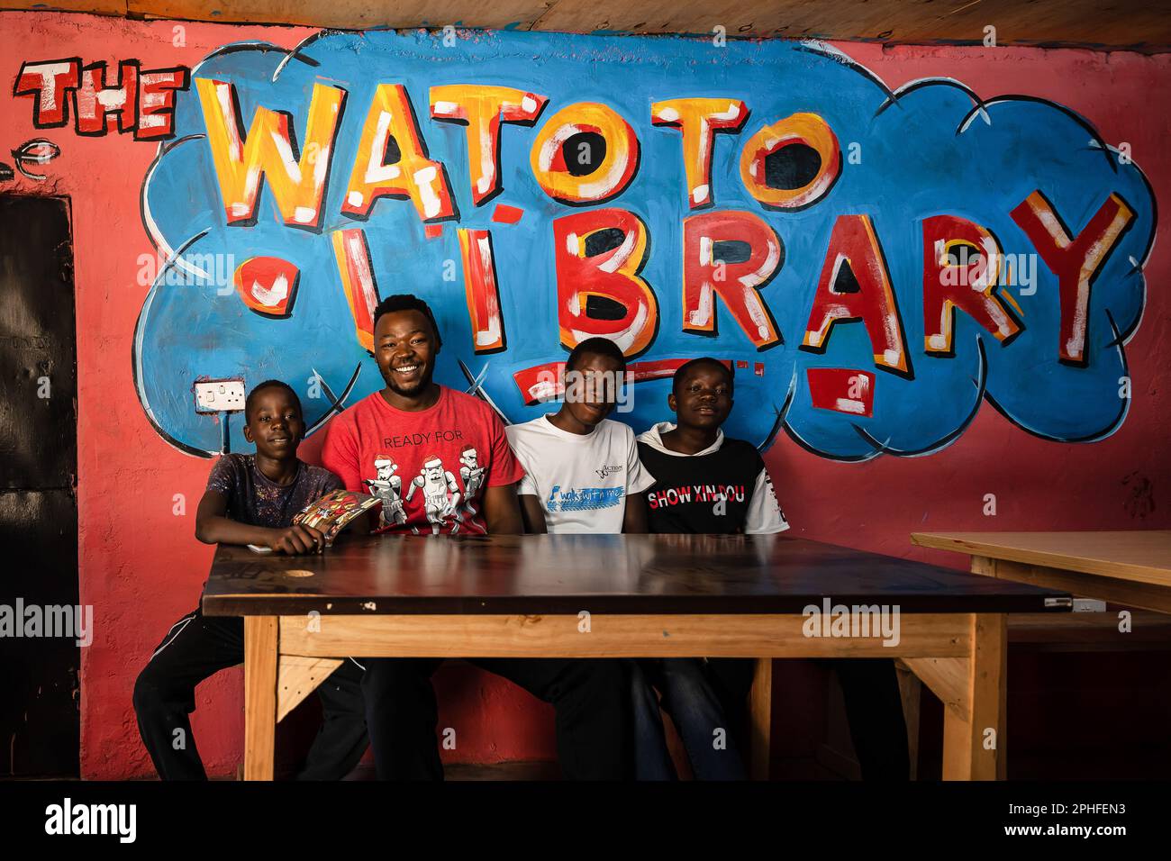 Der Gründer von Kiberas WatotoBibliothek posiert mit 3 Kindern des