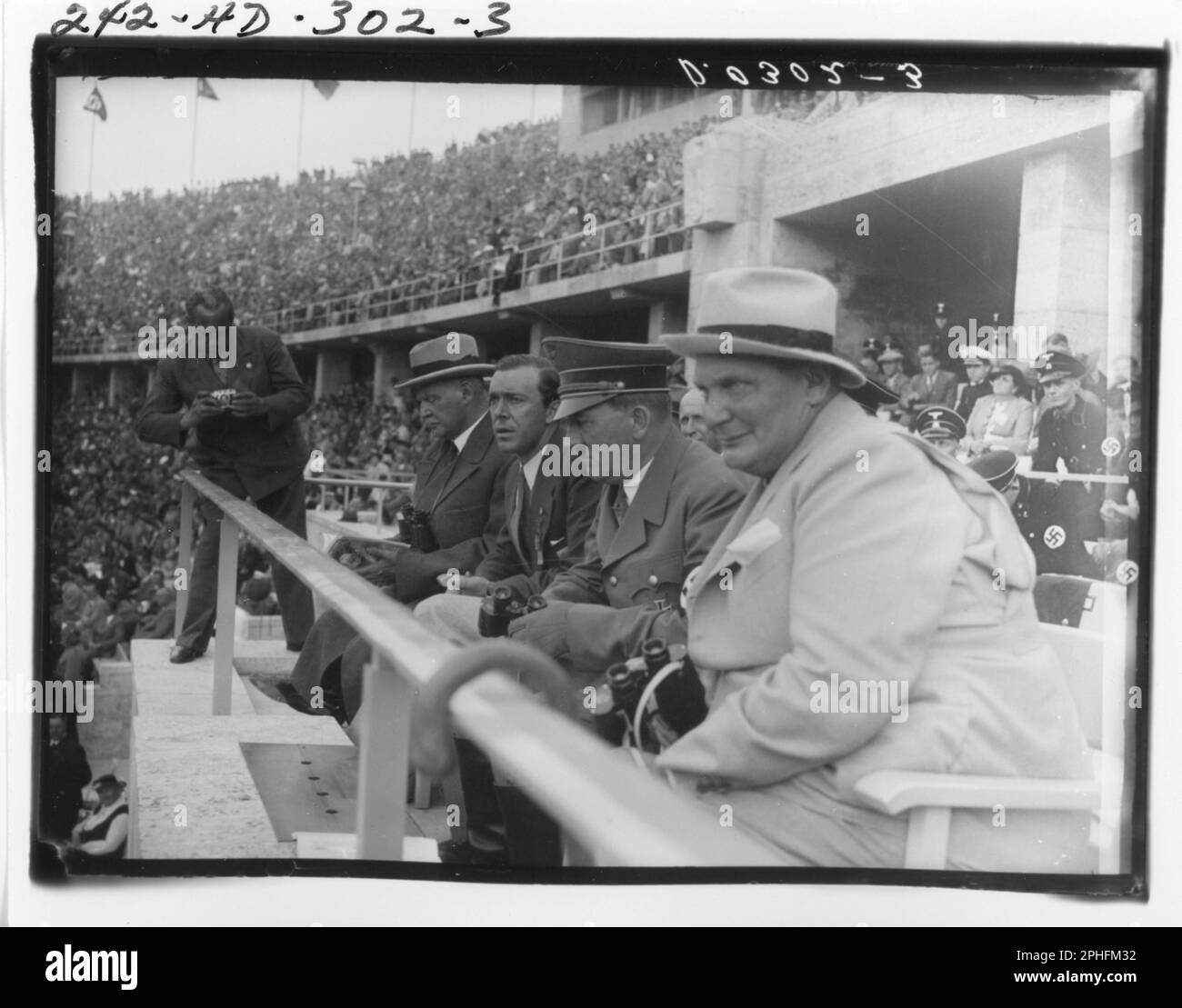 Ein unidentifizierter Fotograf (links stehend) macht ein Foto, während Adolf Hitler und andere Nazi-Funktionäre wie Herman Göring (ganz rechts) die Olympischen Spiele vom Stadion aus, Berlin, 8/1936, ansehen. (Foto von National Archives and Records Administration Stockfoto