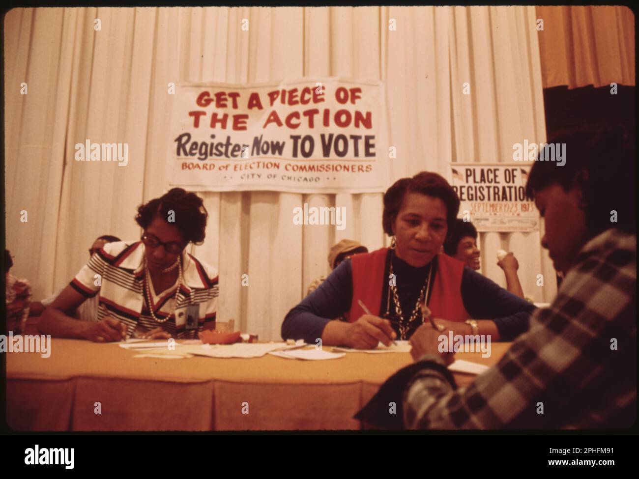 Freiwillige für Chicagos Wahlausschuss-Kommissare registrieren neue Wähler unter einem Schild mit der Aufschrift „Get a Piece of the Action, Register Now to Vote“, Chicago, IL, 9/23/1973. (Foto: US National Archives and Records Administration Stockfoto