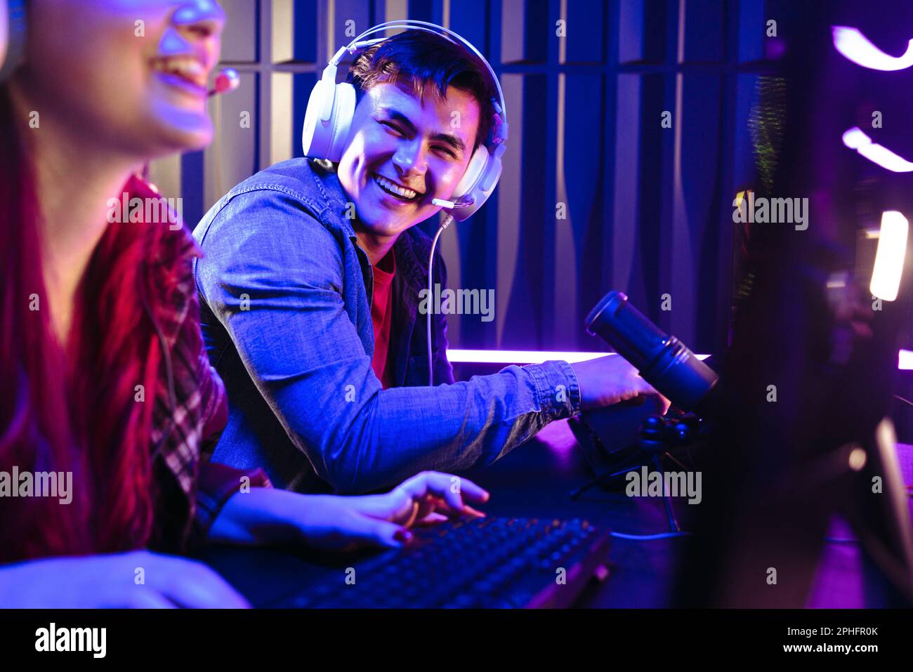 Männlicher Spieler, der stolz lächelt, nachdem er seinen Mitbewerber in einem Online-Gaming-Wettbewerb geschlagen hat. Zwei junge Gamer, die Videospiele auf ihren Computern spielen, mit Stockfoto