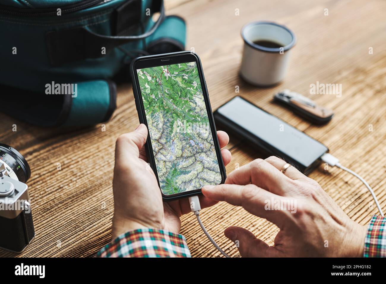 Mann, der die nächste Urlaubsreise während der Reise plant, sucht Reiseziel und Routen mithilfe der Navigationskarte auf dem Mobiltelefon. Laden des Smartphones mit p Stockfoto