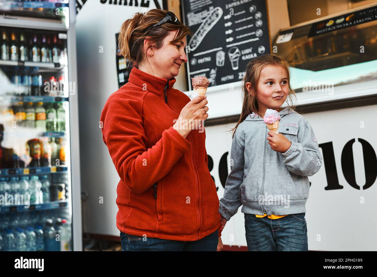 Mutter und ihre Tochter essen Eis auf einem sitzen Treten Sie in den Sommerferien vor den Foodtruck Stockfoto