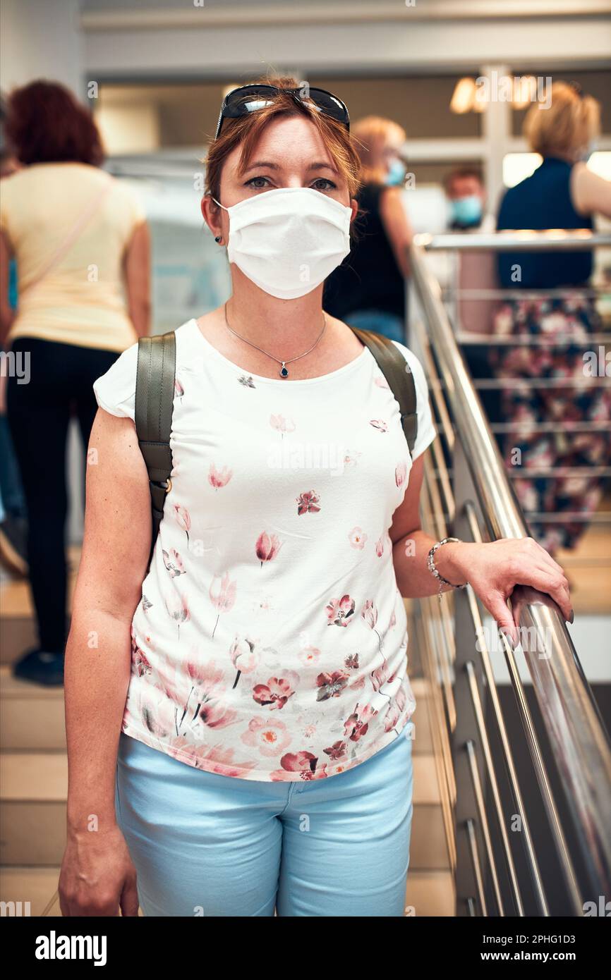 Frau geht unten in öffentlichen Platz innen tragen Gesichtsmaske Zur Abdeckung von Mund und Nase während des Ausbruchs des pandemischen Coronavirus Stockfoto