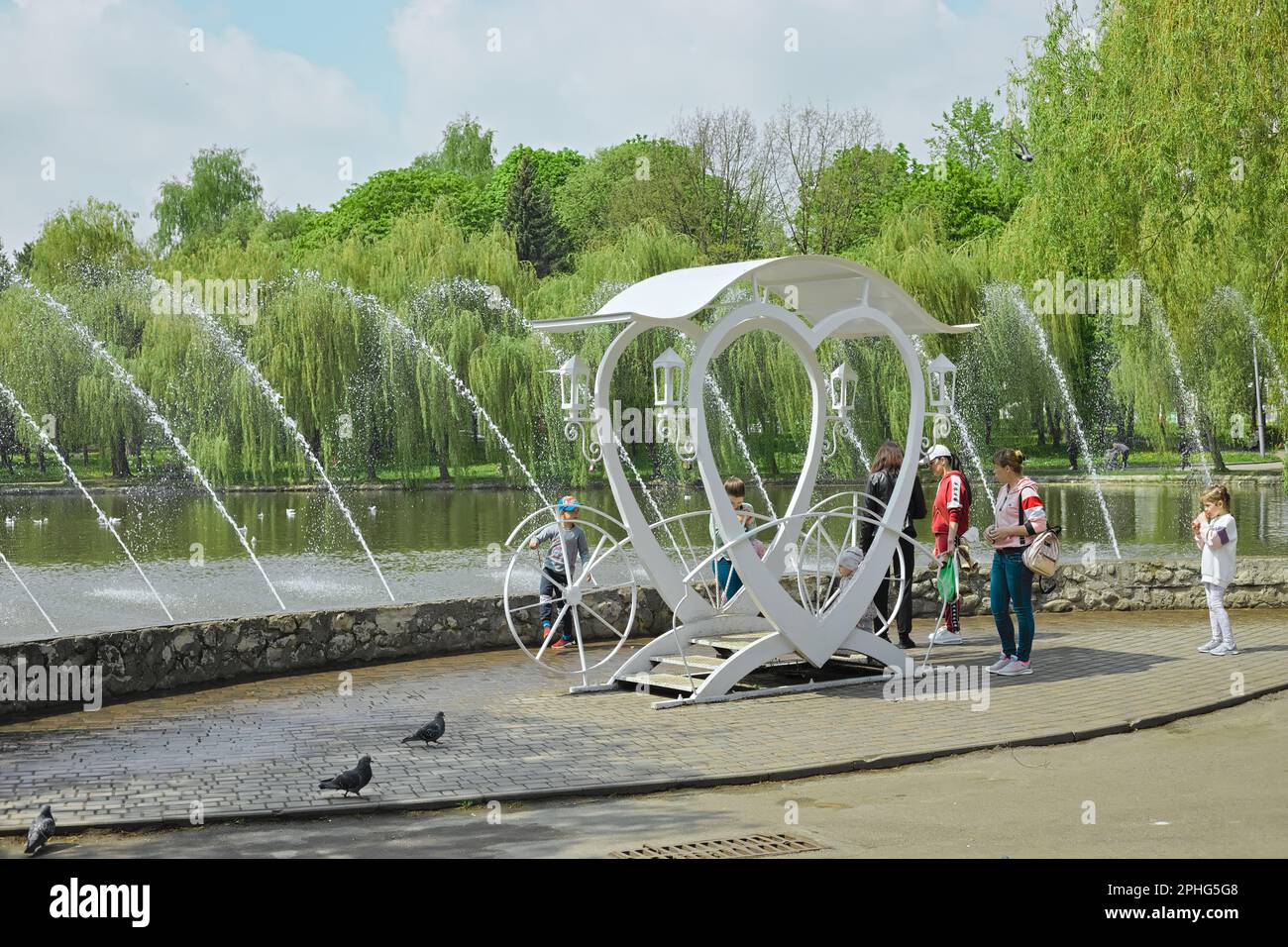 Rivne, Ukraine, 5. Mai 2022: Ort für ein Foto in Form einer herzförmigen Kutsche in einem Stadtpark in der Nähe eines Sees mit Brunnen Stockfoto