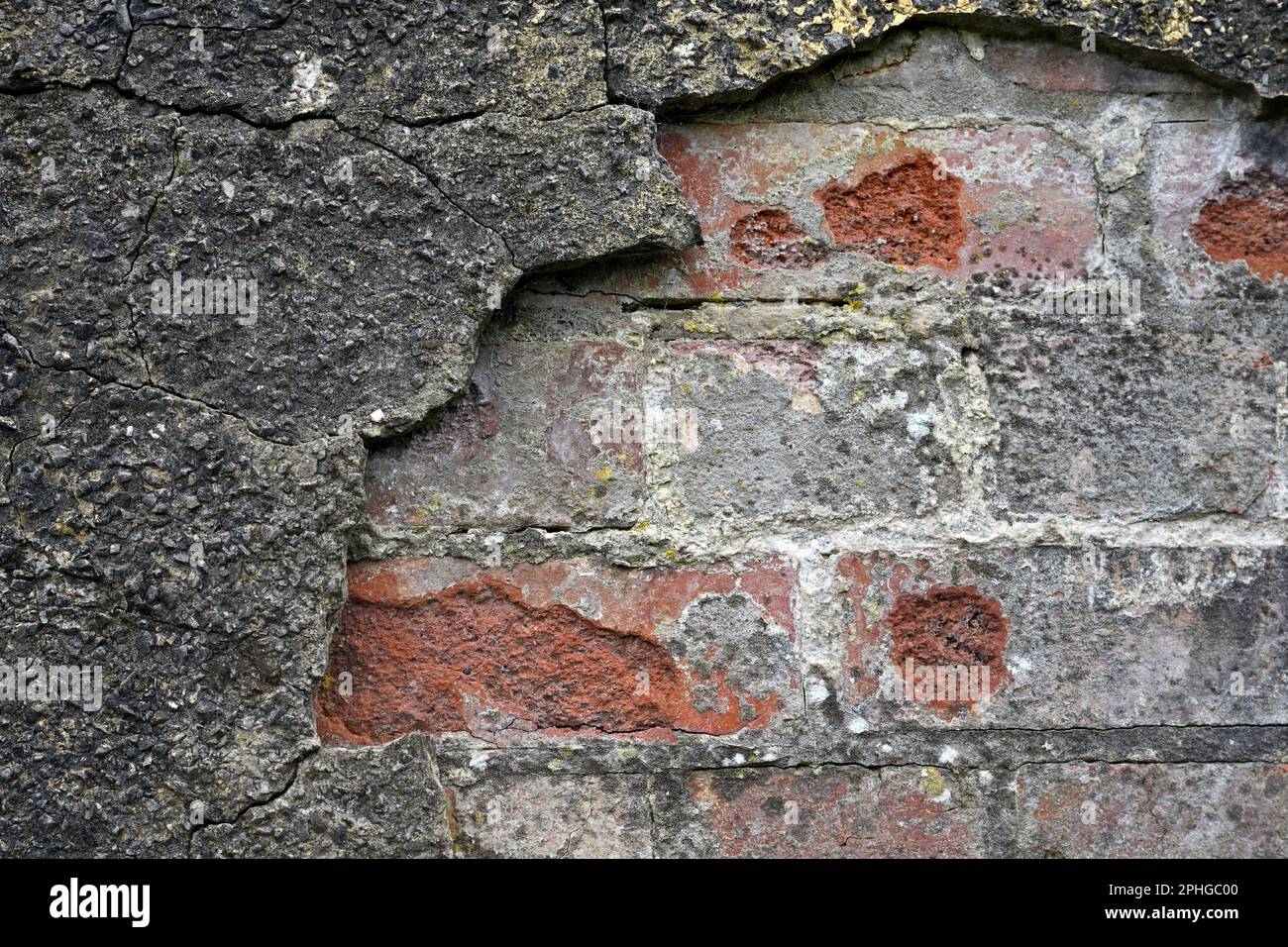Backsteinwand mit hartem Zement, der rissig ist und abfällt Stockfoto