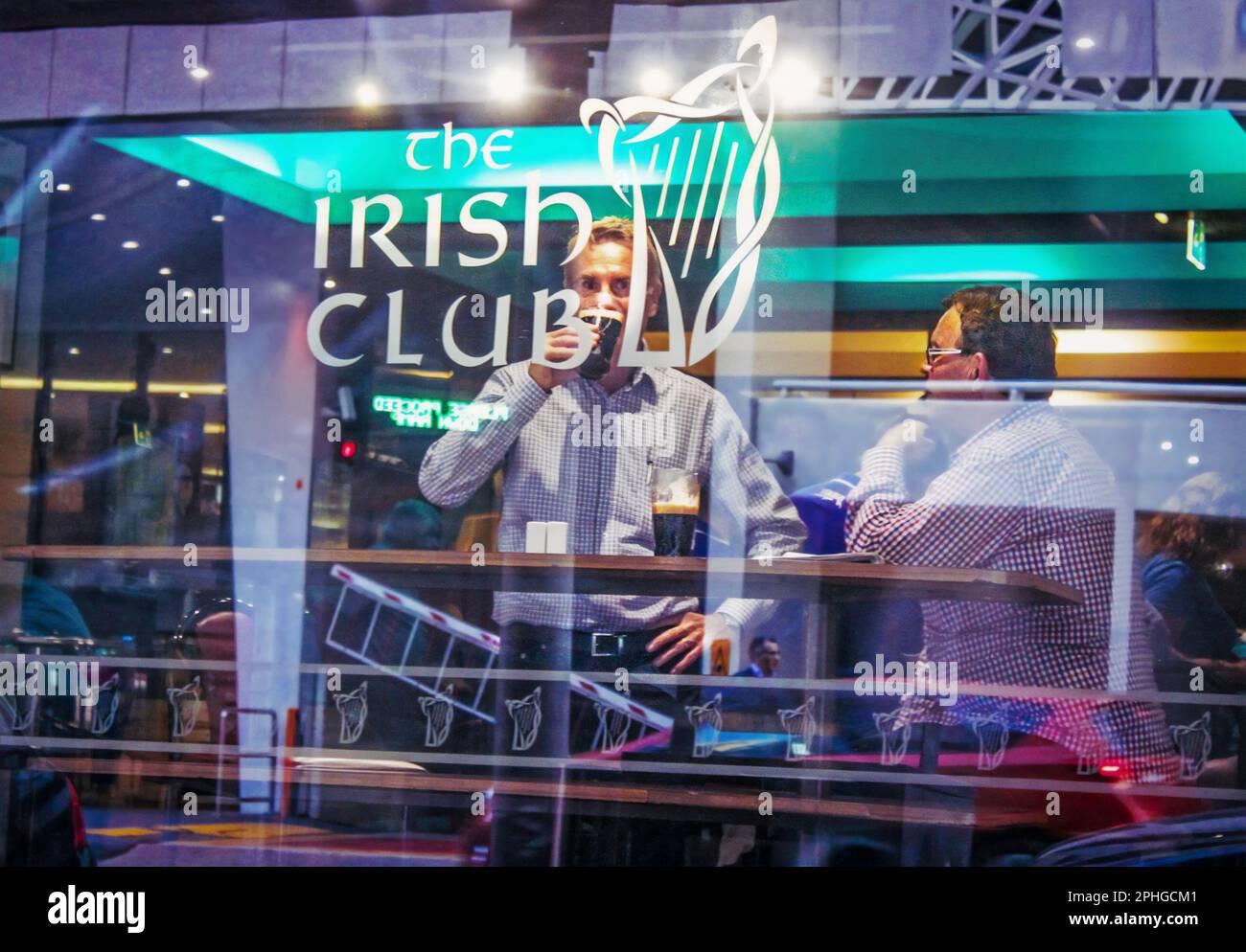2015 - 03 Uhr Brisbane Australien - Straßenfotografie im Fenster des irischen Clubs - zwei Männer am Tisch am Fenster, die dunkles Bier trinken - Reflexionen der Stadt im Wind Stockfoto