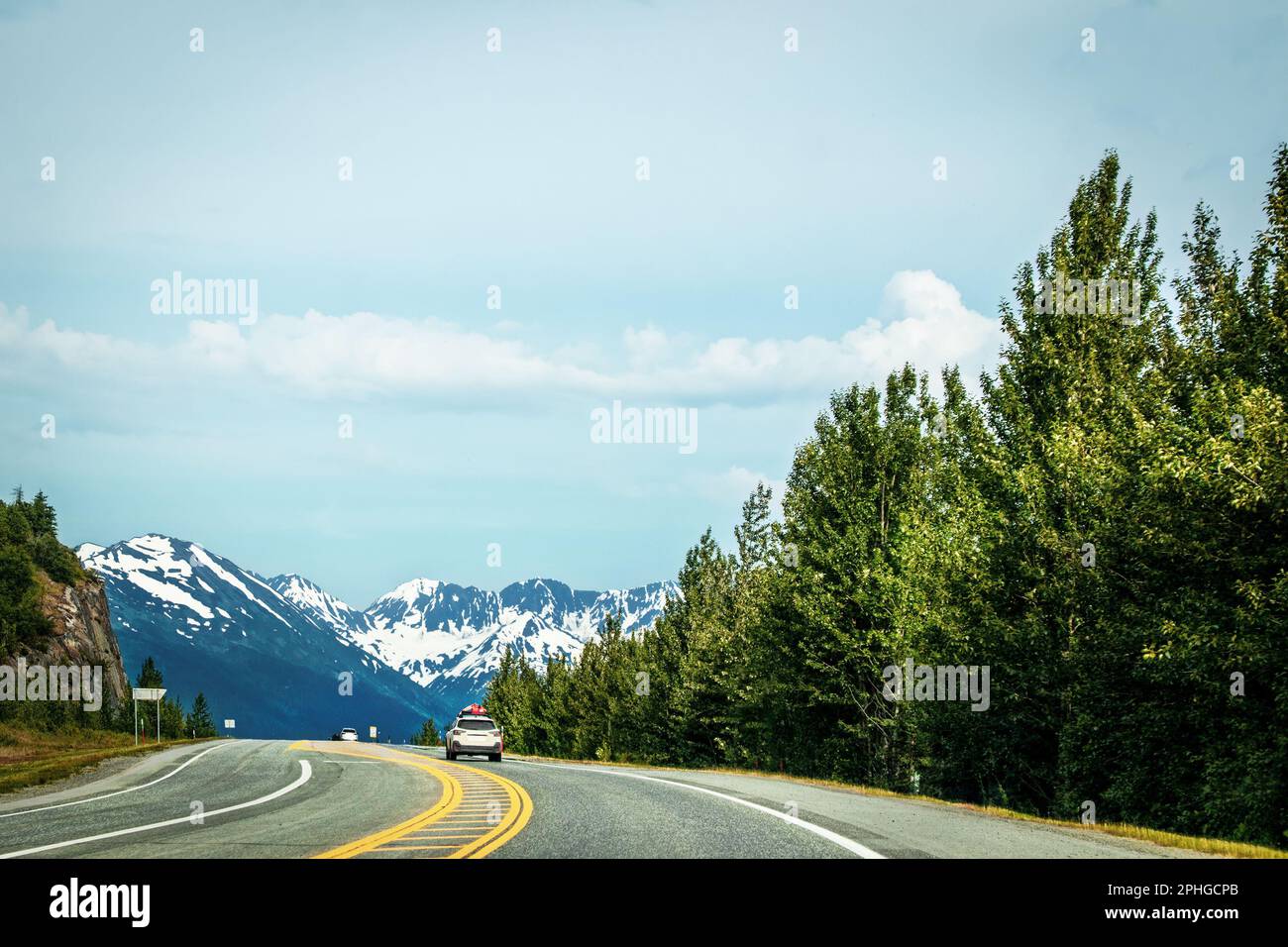 Fahrt von Anchorage nach Seward Alaska auf dem Highway 9 South auf der Kenai-Halbinsel mit schneebedeckten Bergen in der Ferne und immergrünen Bäumen auf der Halbinsel Stockfoto