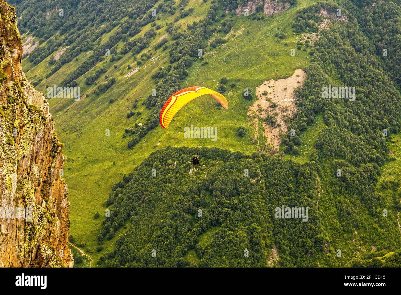 Tandem-Fallschirm mit Fallschirm – Gleitschirmfliegen in Georgia in der Nähe riesiger Klippen über Bäume im weit unten gelegenen Tal Stockfoto