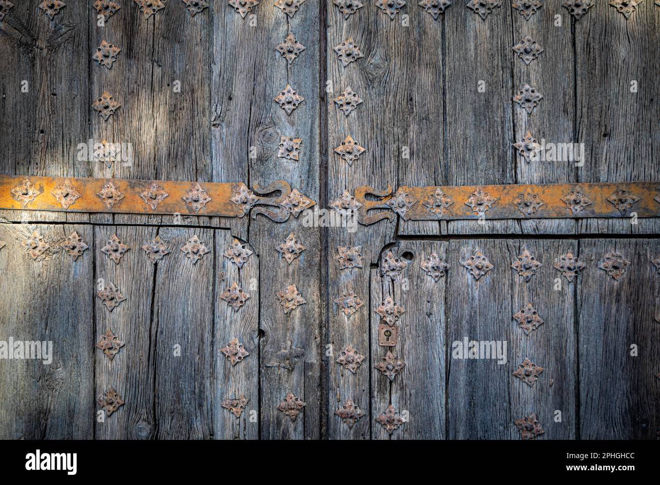 Gealterte zweiflügelige Holztür mit Metallschmuck, die Blumen und Formen simuliert Stockfoto