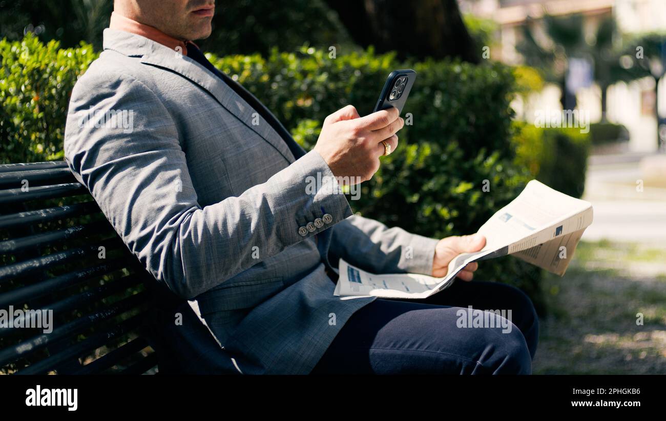 Ein Mann Mit Telefon Liest Zeitung Stockfoto