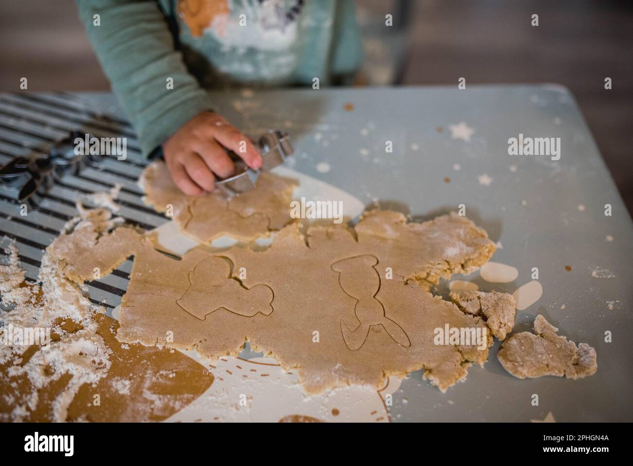 Ein Kind schneidet Kekse aus, backt Lebkuchen mit Kindern, Osterthema - Keksschneider in Form eines Hasen, Zeit mit Kindern, lernt Stockfoto