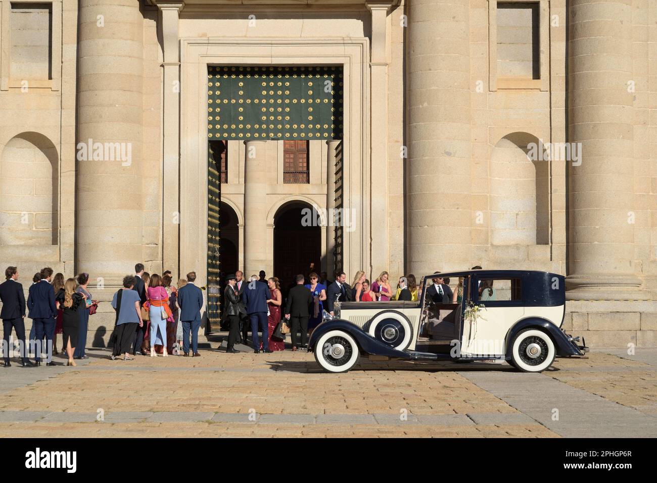 Brautwagen und Gäste warten auf die frisch Vermählten vor den Türen des Klosters San Lorenzo de El Escorial in der Gemeinde Madrid. Stockfoto