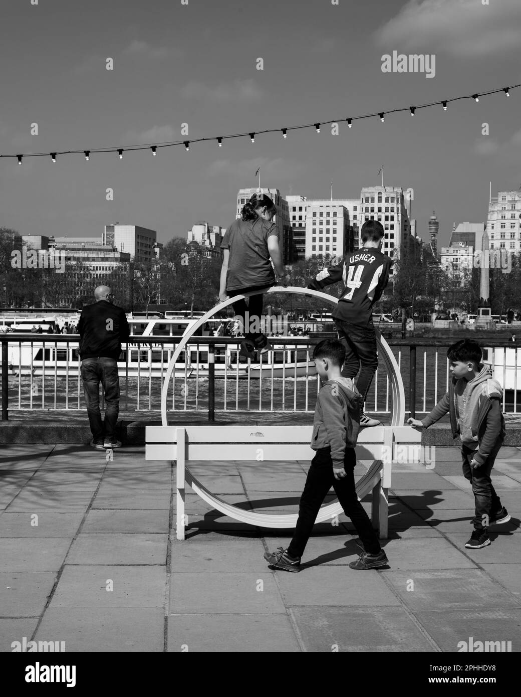 Drei Kinder, die auf einer Bank in der Nähe von Embankment spielen, schwarz und weiß Stockfoto