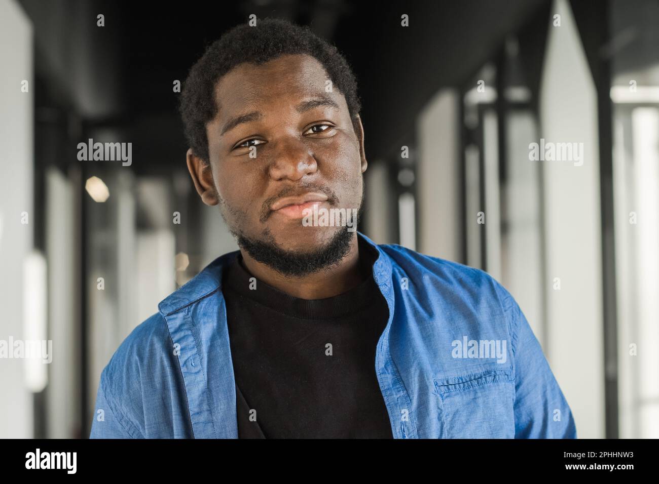 Portrait eines glücklichen afroamerikanischen Kleinunternehmers. Ein junger schwarzer, männlicher Teamleiter, der lächelt, in die Kamera schaut, Mitarbeiter, die in der Moderne arbeiten Stockfoto