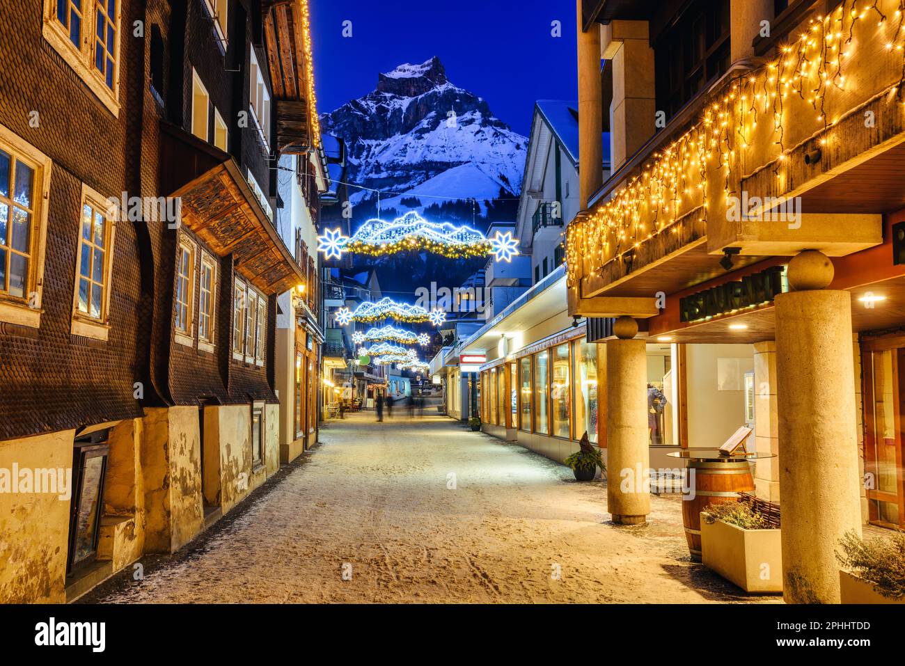 Weihnachtsdekorationen und traditionelle hölzerne Chalet-Häuser in einer Straße in der Altstadt des Dorfes Engelberg, einem beliebten Skigebiet in den Alpen Stockfoto
