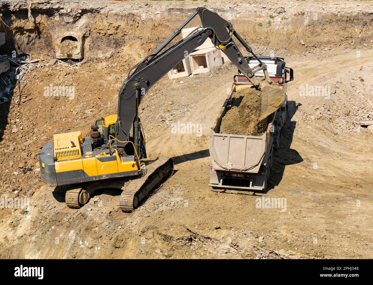 Bagger und Lkw arbeiten im Baugewerbe, beladen auf Lkw Stockfoto