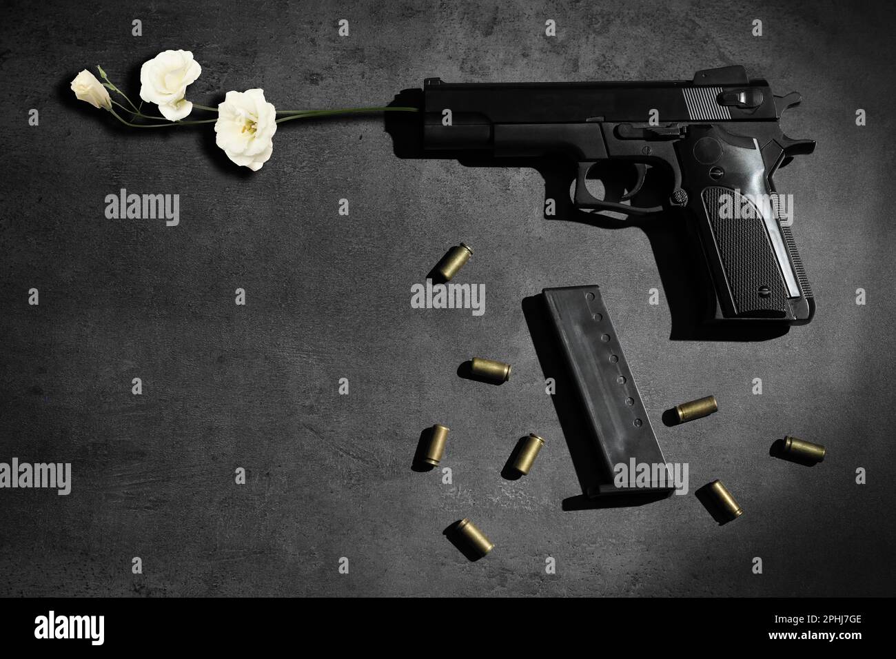 Wunderschöne Blumen, Kugeln und eine Pistole auf einem grauen Tisch, flach liegend. Frieden statt Krieg Stockfoto