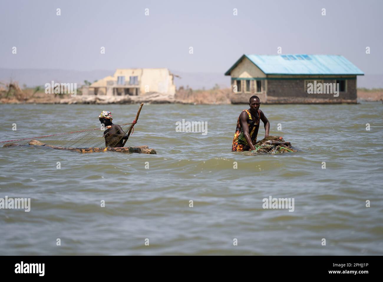 Kalokol, Kenia. 14. Februar 2023. Zwei Fischer, die mit ihren Netzen im Turkana-See spazieren. Das Dorf Kalokol ist in den letzten Jahren überflutet worden, weil der Turkana-See und alle anderen Seen des Rift Valley aufgrund des Klimawandels enorm angestiegen sind. Dieses Phänomen hat ganze Dörfer überschwemmt, die Bevölkerung gezwungen, ihre Häuser und Geschäfte aufzugeben, und hat verheerende Auswirkungen auf die natürlichen Ökosysteme. (Foto: Simone Boccaccio/SOPA Images/Sipa USA) Guthaben: SIPA USA/Alamy Live News Stockfoto