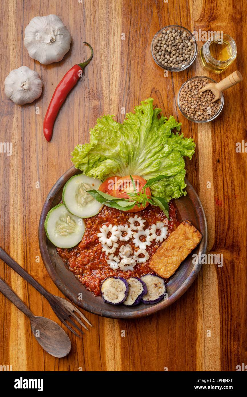 Knusprige gebratene Calamari mit scharfer Chilisauce oder Sambal auf Töpferteller auf Holztisch Stockfoto