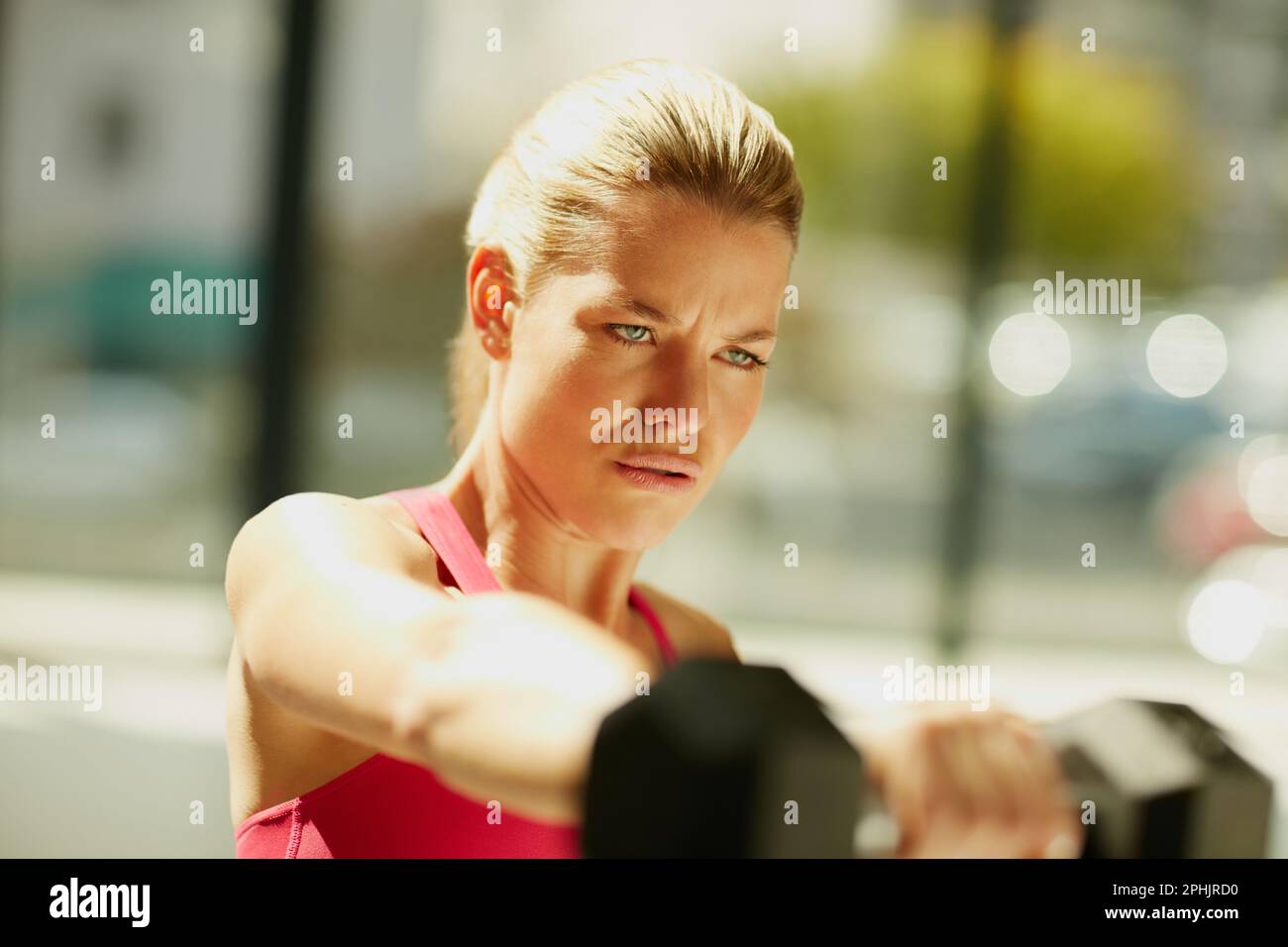 Konzentriert sich darauf, fitter zu werden. Eine attraktive junge Frau, die mit Kurzhanteln trainiert. Stockfoto