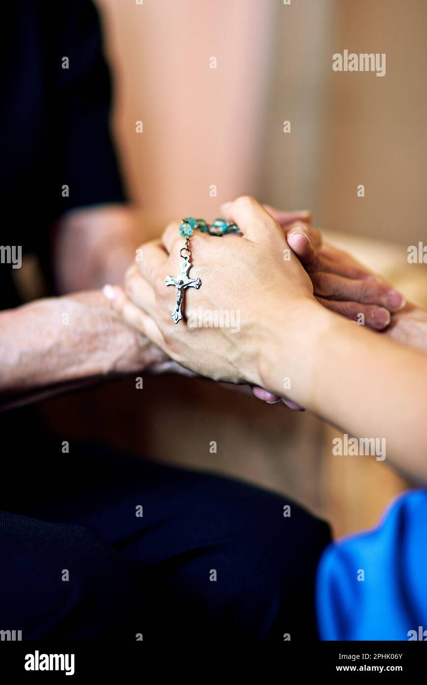 Ihre Güte ist vom Himmel gesandt. Eine Person, die mitfühlend einen Rosenkranz hält, und eine ältere Frau, die Hände hält. Stockfoto