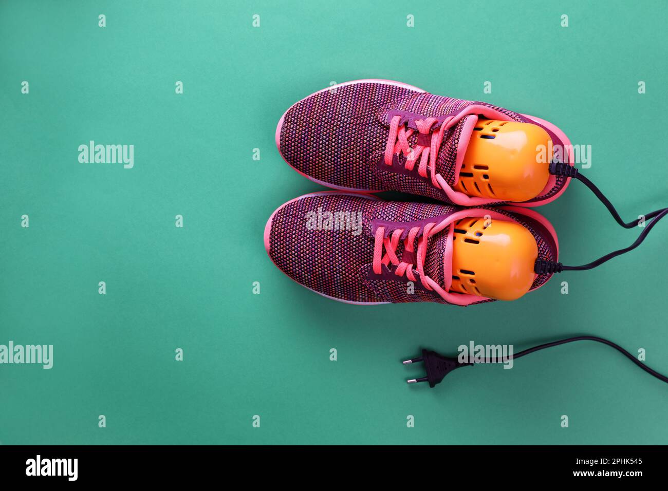 Stylische Sneaker mit modernem elektrischen Schuhtrockner auf grünem Hintergrund, Draufsicht. Platz für Text Stockfoto