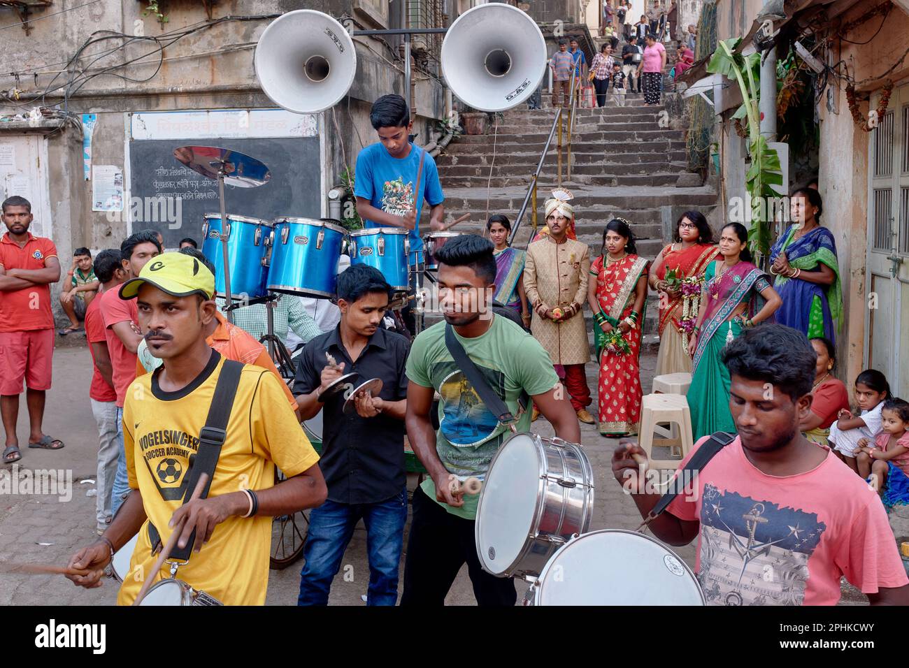 Während einer unauffälligen indischen Hochzeit spielt eine Amateur-Hochzeitsband in einem Hinterhof in Mumbai, Indien, mit dem Paar und seinen Freunden im Hintergrund Stockfoto