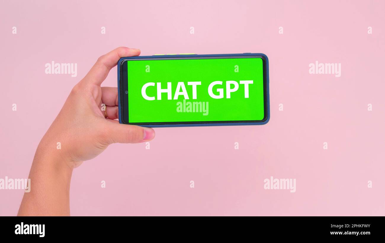 Mit der Hand gehaltenes Smartphone mit grünem Chat-GPT-Bildschirm in horizontaler Position isoliert auf pinkfarbenem Hintergrund. Chatbot-Assistent oder künstliches i Stockfoto