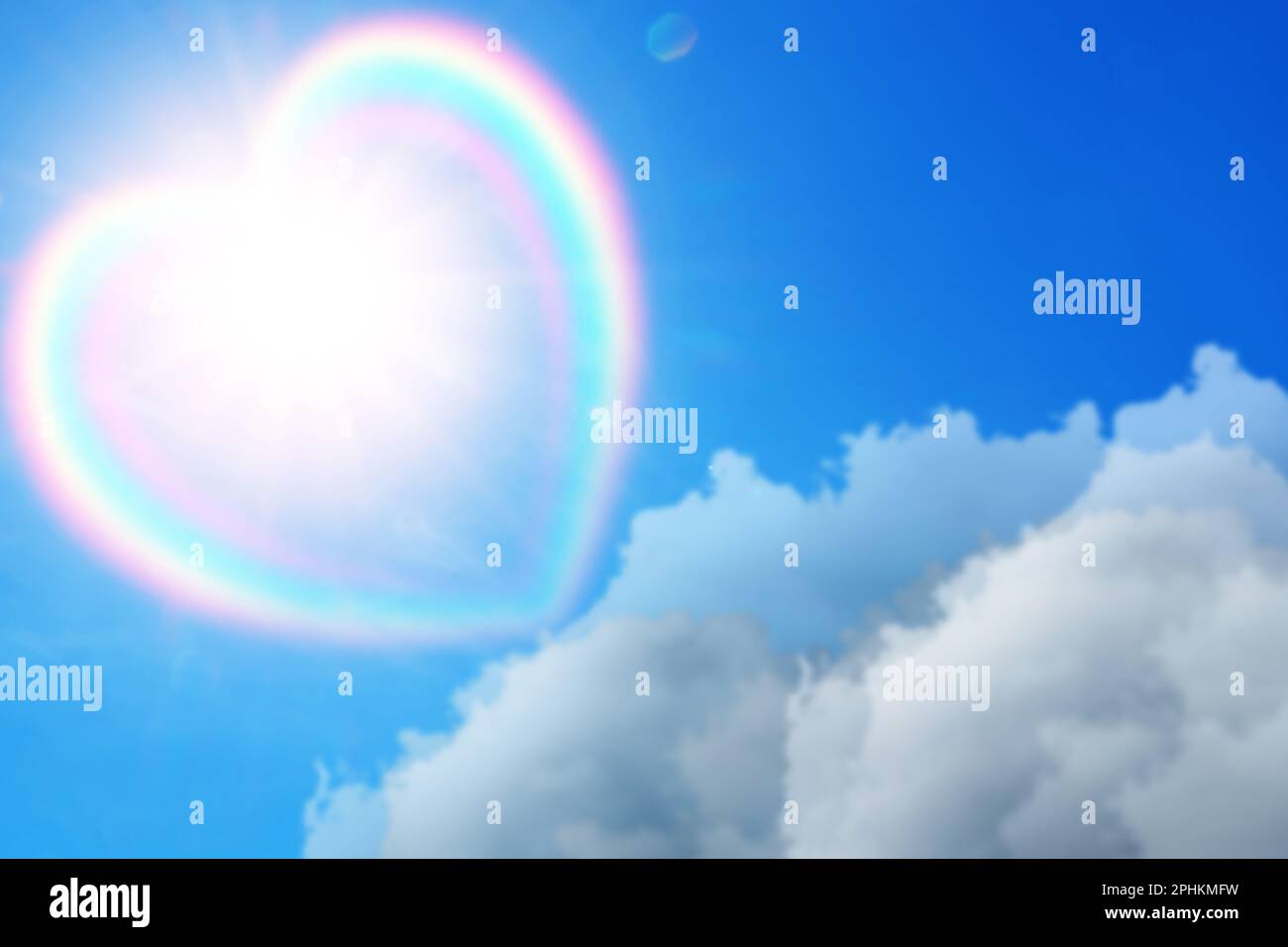 Wunderschöner Blick auf die herzförmige Wolke mit Regenbogen am blauen Himmel an sonnigen Tagen Stockfoto
