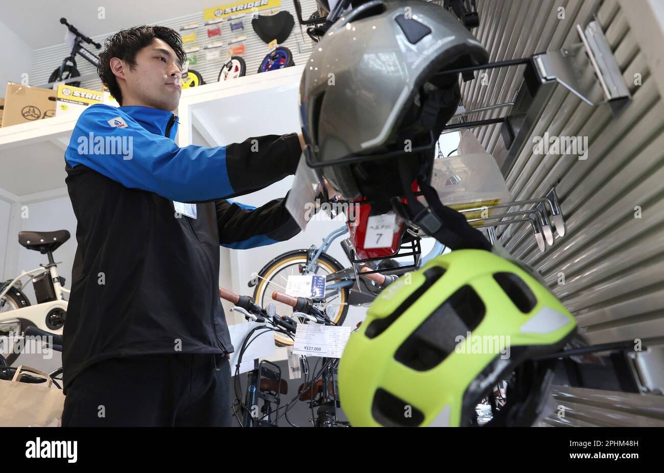 An employee of Cycle Base Asahi shows bicycle helmets in Shibuya Ward, Tokyo on March 29, 2023. Japanese government amended the Road Traffic Act and every bicycle user will be required to wear a bicycle helmet when riding a bicycle from April 1st. ( The Yomiuri Shimbun via AP Images ) Stockfoto