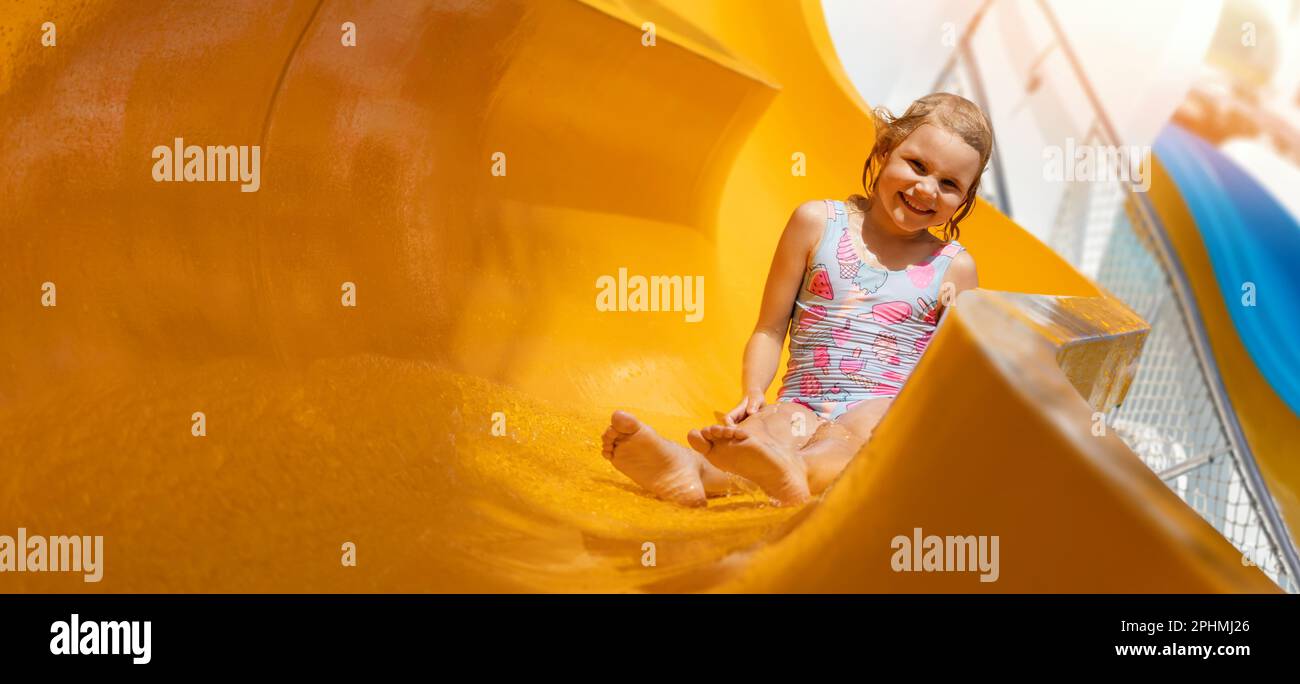 Glückliches kleines Mädchen auf Rutsche im Outdoor Wasserpark. Banner mit Kopierbereich Stockfoto